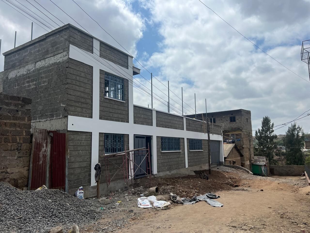 Stone-walled school block with planters and fenced rooftop area