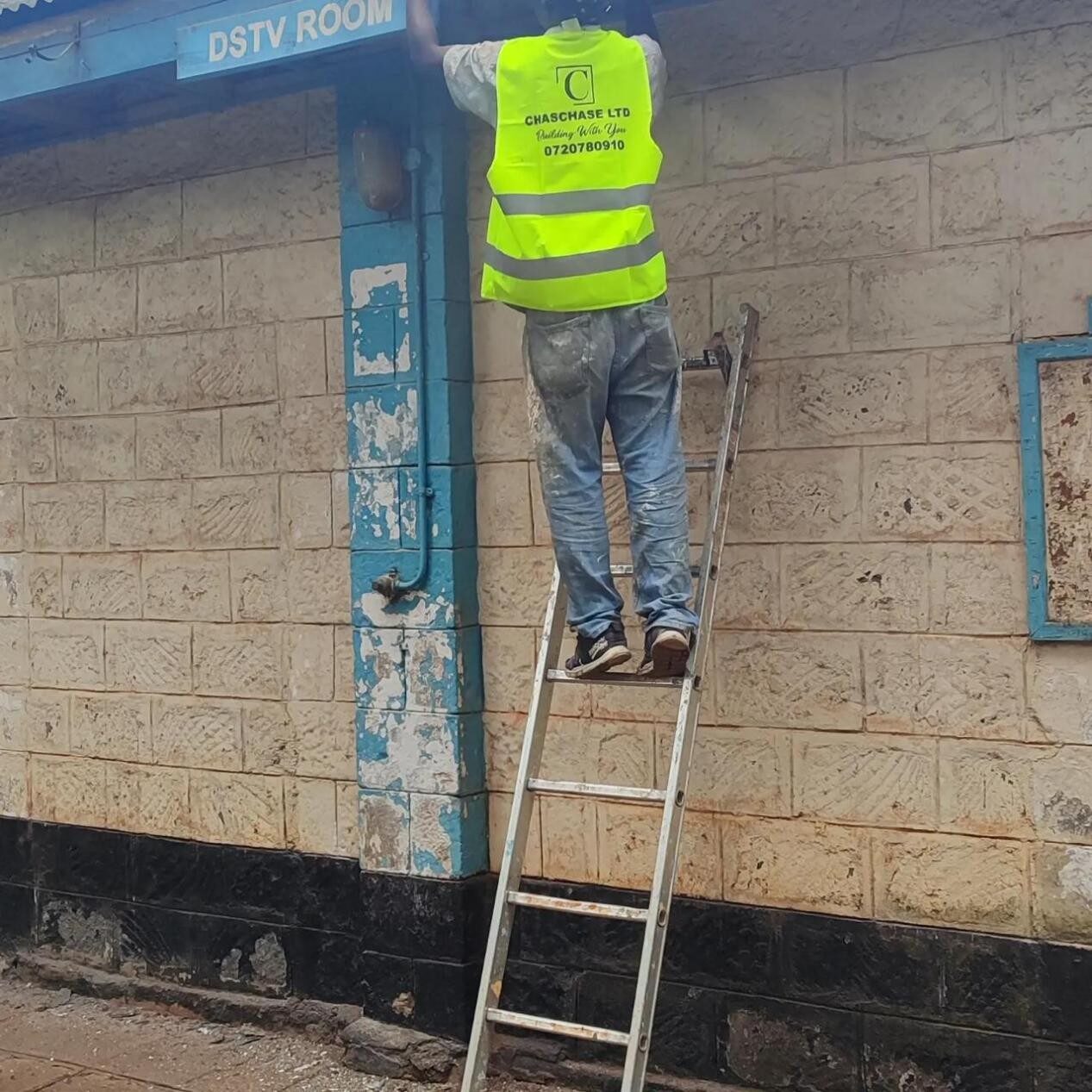 Chaschase worker in branded vest on a ladder at the campus DSTV room